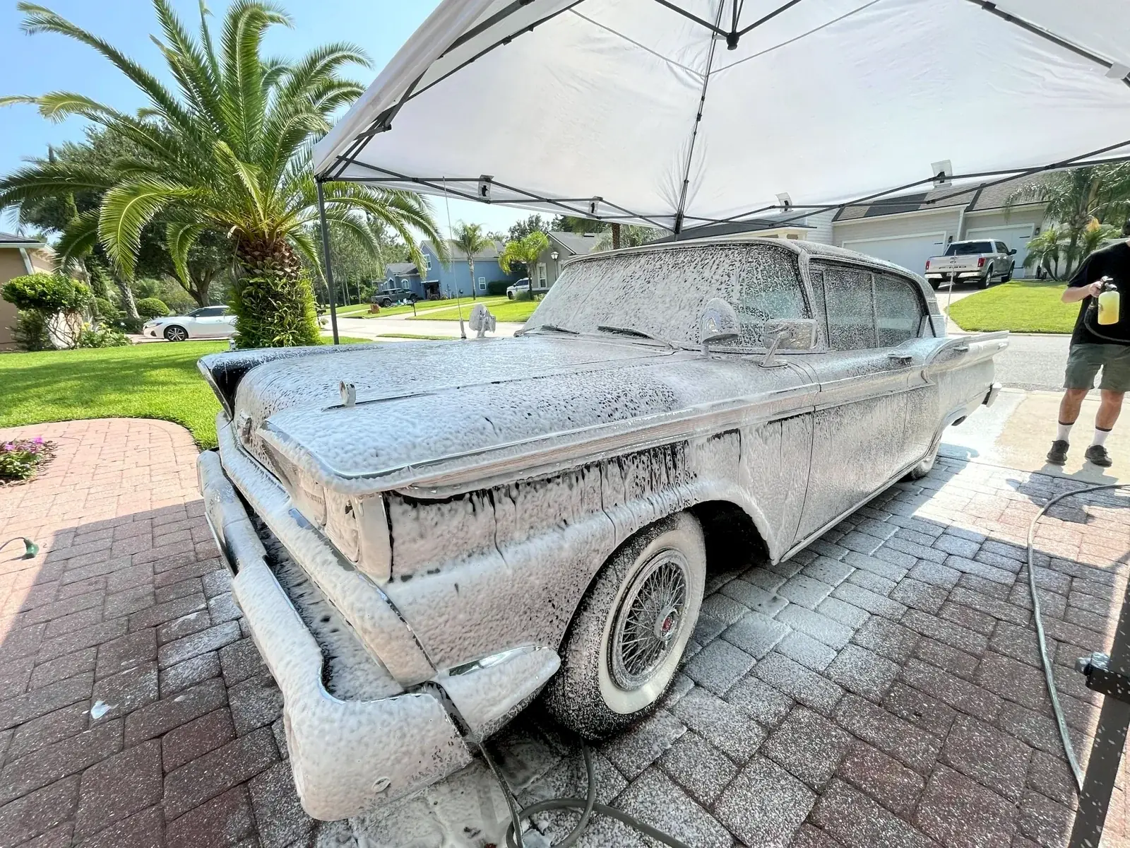 The same 1959 Ford covered in snow foam during the wash